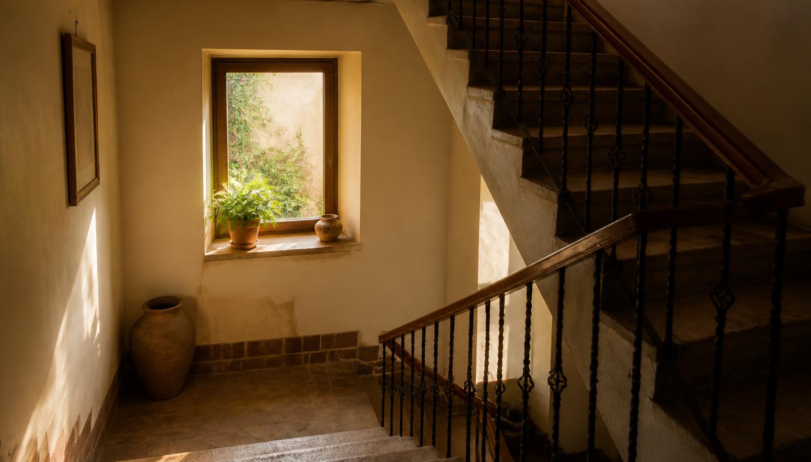 Warmes Treppenhaus mit sanftem Lichteinfall, Holzgeländer und Naturstein